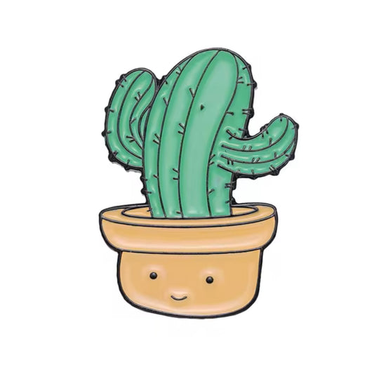 An enamel pin shaped like a happy cactus in a pot with a smiling face.