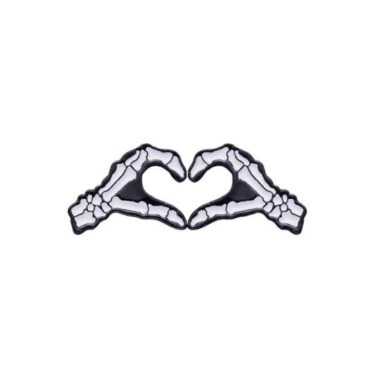 An enamel pin shaped like two skeleton hands forming a heart symbol.