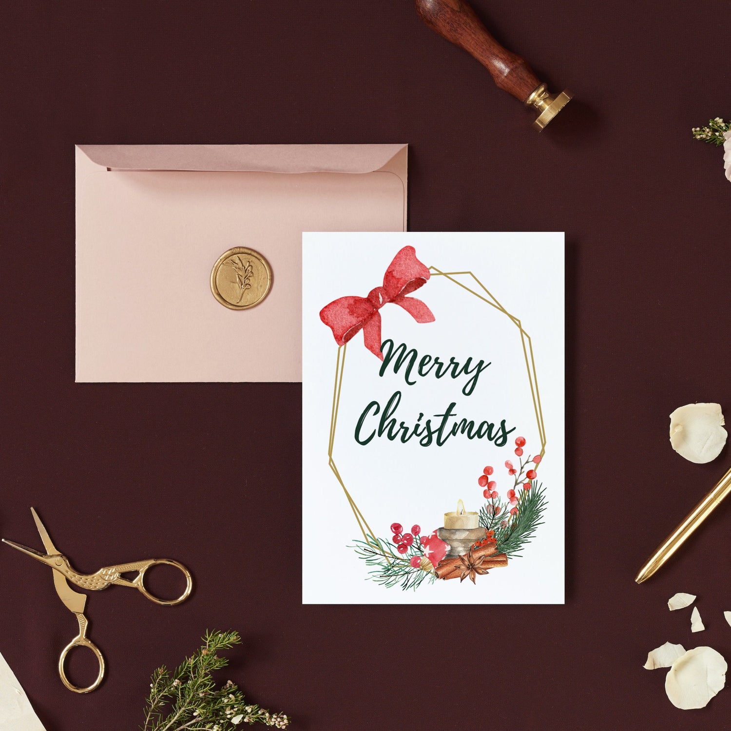 A simple yet elegant Christmas card with a red bow and green holiday-themed decorations on a brown background, accompanied by a pink envelope and a pair of scissors.