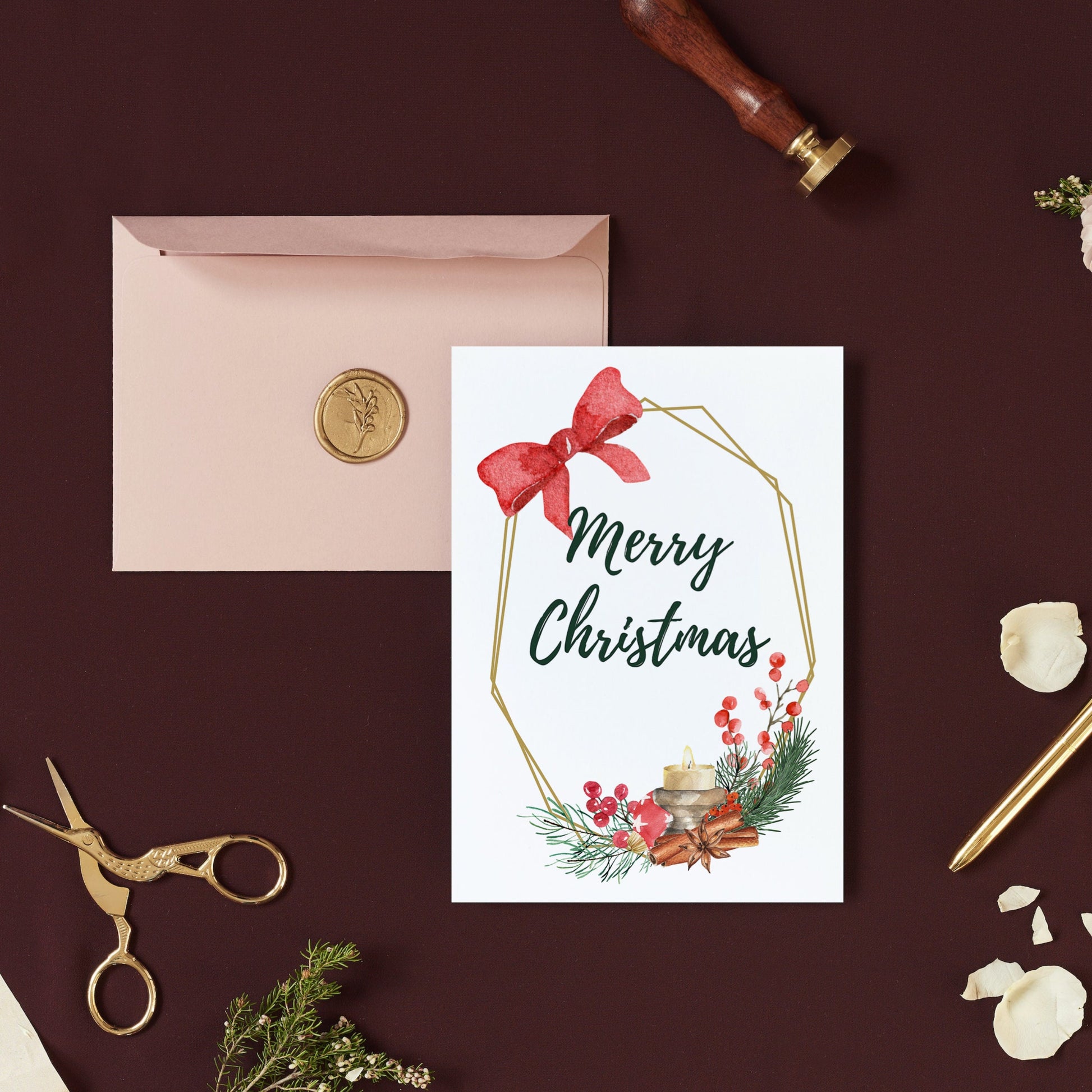A simple yet elegant Christmas card with a red bow and green holiday-themed decorations on a brown background, accompanied by a pink envelope and a pair of scissors.